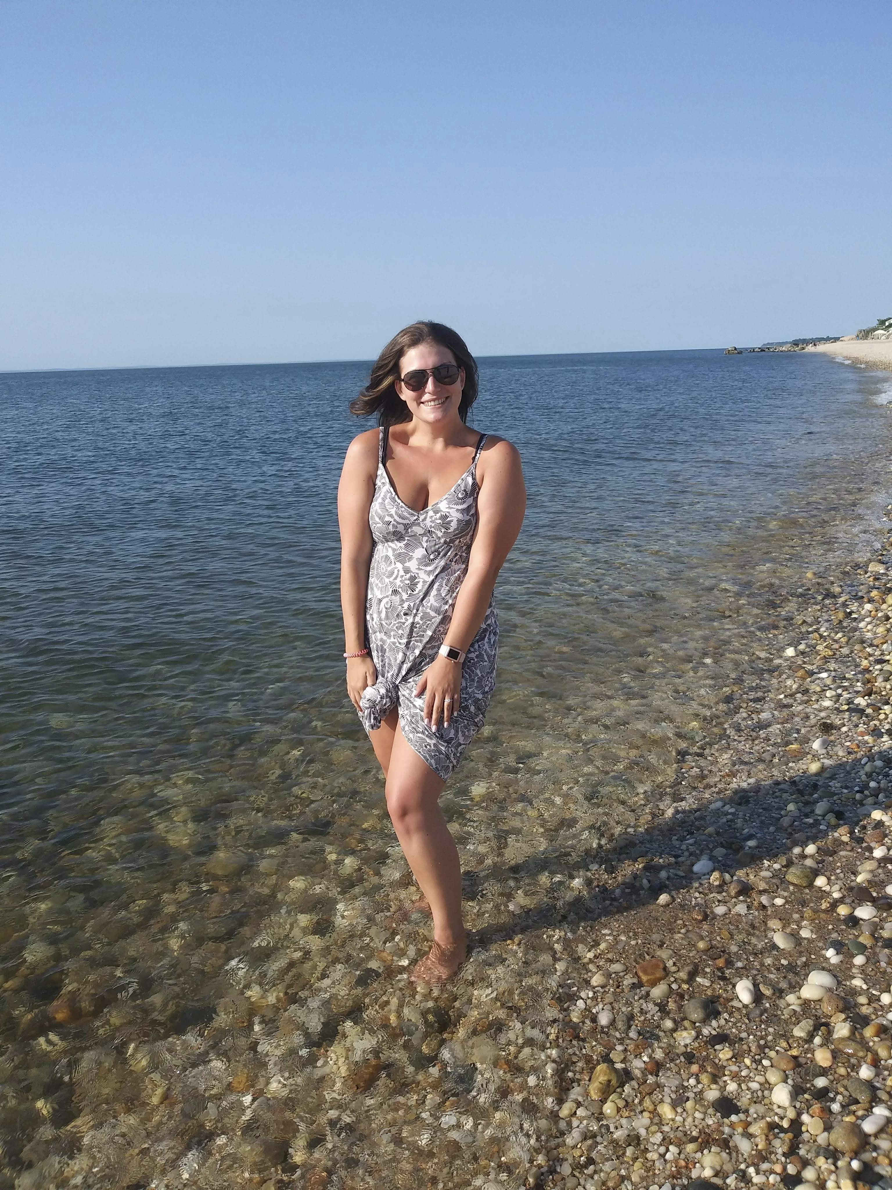 Valerie standing by the water on a rocky beach.